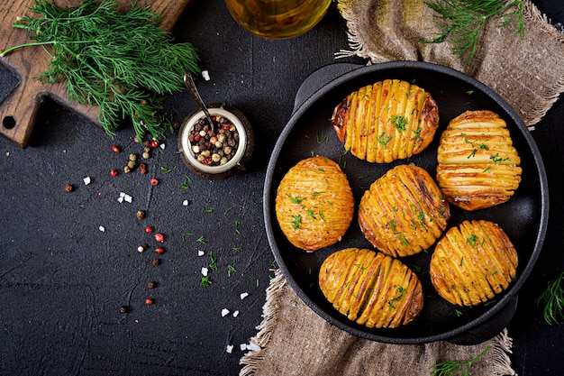 Pomme de terre au four avec des herbes sur fond noir. Nourriture végétalienne. Repas sain.