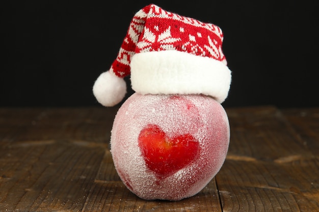 Pomme de vacances avec coeur givré sur une table en bois sur une surface noire