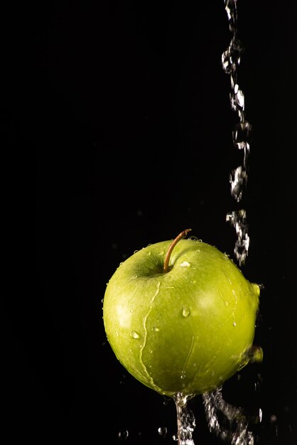 Pomme verte avec de belles éclaboussures d'eau avec fond noir et mise au point sélective.