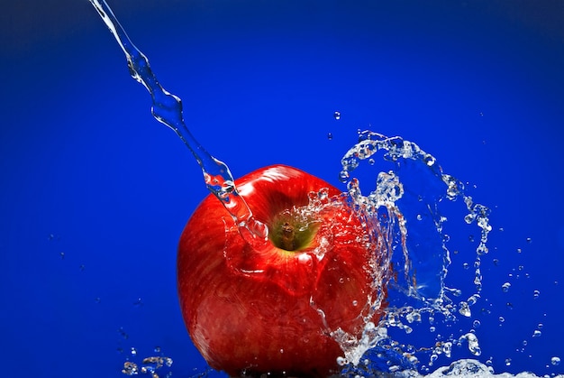 Pomme verte avec des éclaboussures d'eau sur le mur bleu