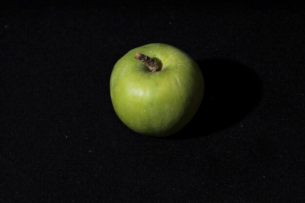 Une pomme verte est sur un fond noir.