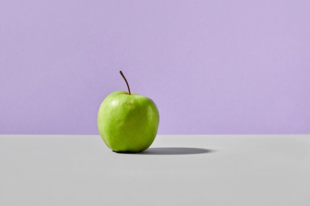 Photo pomme verte sur un fond violet gris concept végétalien élégant
