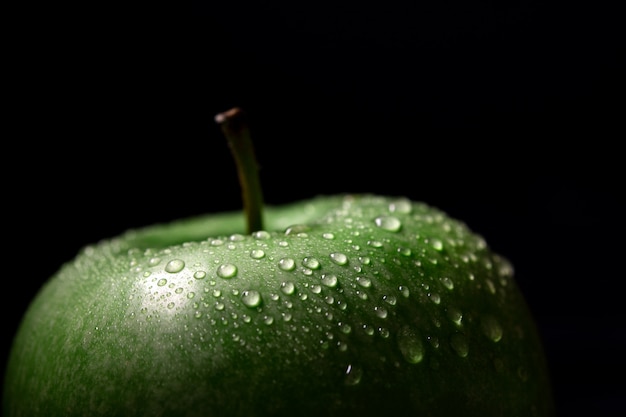 Pomme verte avec des gouttes sur un mur sombre