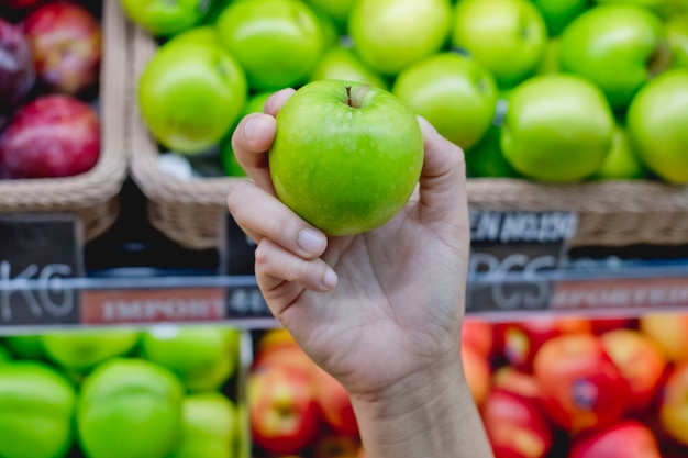 Pomme verte à la main avec fond de fruits