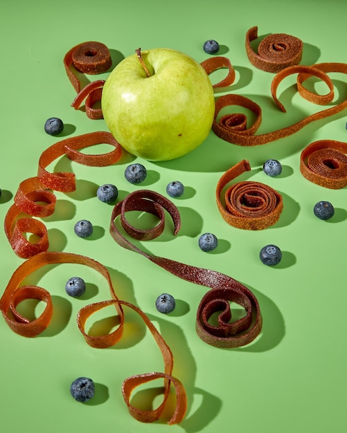 Pomme verte parmi les pastilles de fruits naturelles en studio vert