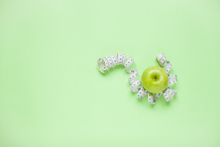 Pomme verte et ruban à mesurer sur fond vert