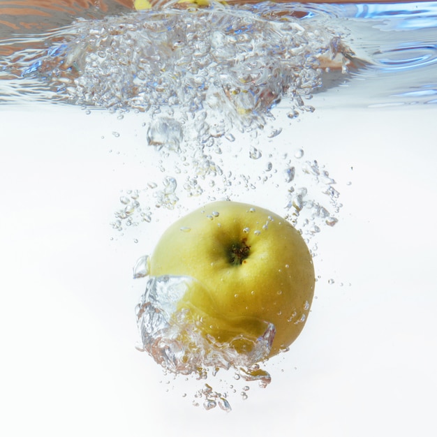 Pomme verte sous l'eau avec une traînée de bulles transparentes