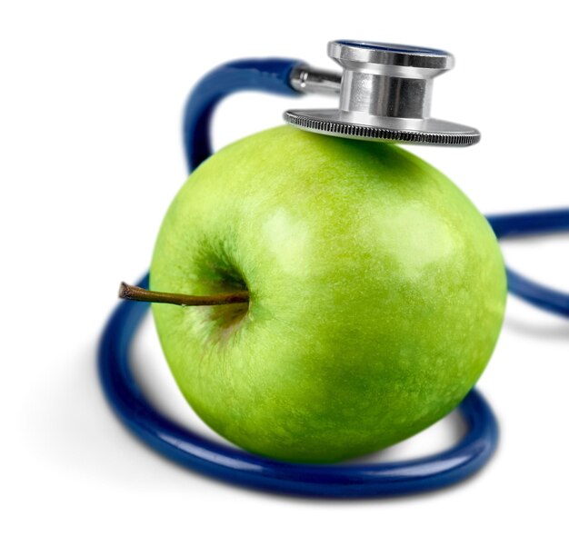 Pomme verte et un stéthoscope sur fond blanc