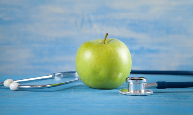 Pomme verte avec stéthoscope sur fond bleu.