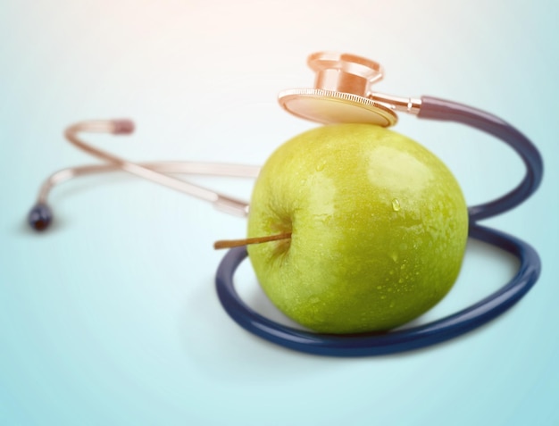 Pomme verte et un stéthoscope sur fond clair