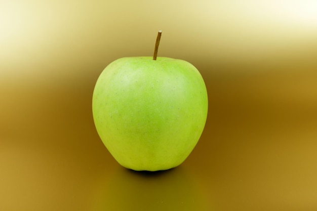 Pomme verte sucrée juteuse sur fond doré Concept d'aliments sains Gros plan d'un fruit vert