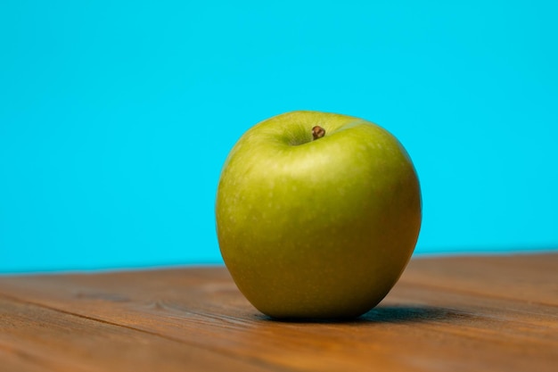 Pomme verte sur une table en bois sur fond bleu