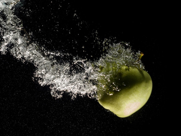 Photo pomme verte tombant dans l'eau