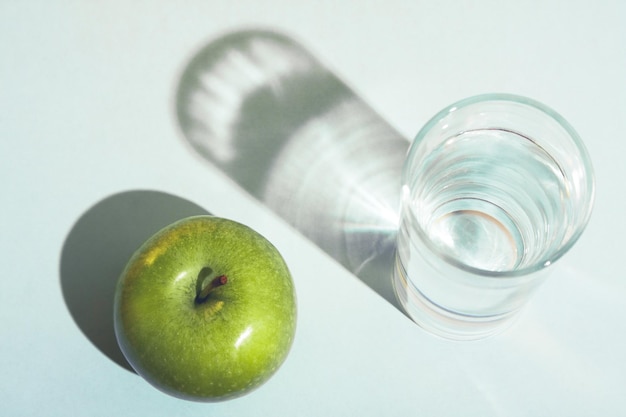 Une pomme verte et un verre d'eau.