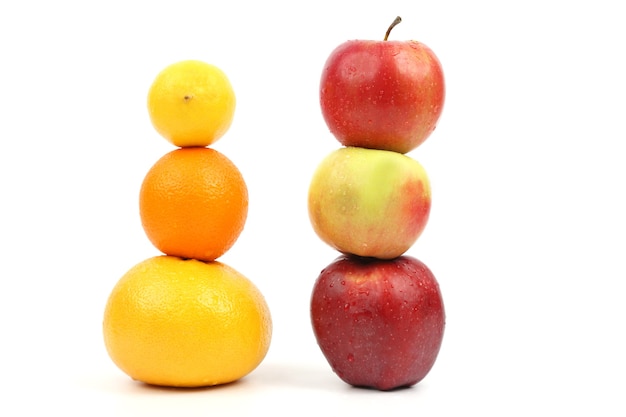 Les pommes et les agrumes se tiennent verticalement les uns sur les autres sur fond blanc