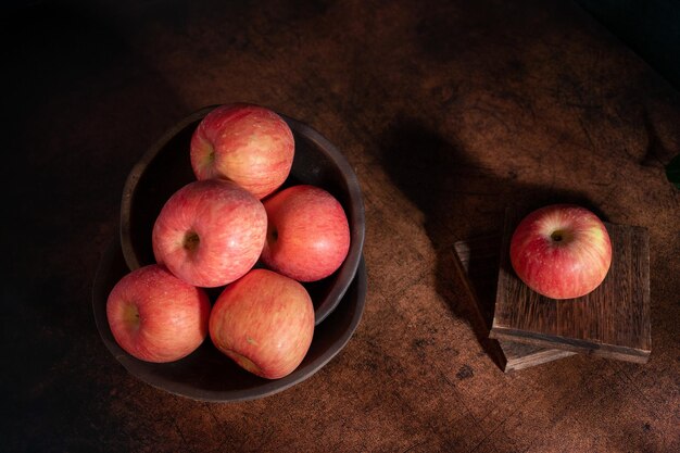 Les pommes sur l'assiette ressemblent à des peintures à l'huile sous la faible lumière sur la table à grain de bois