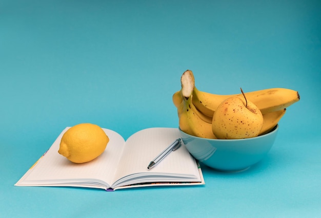 Photo pommes bananes et cahier sur fond bleu