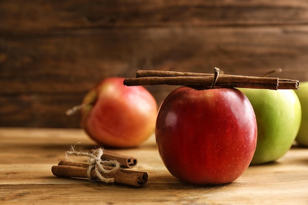 Pommes avec des bâtons de cannelle sur fond de bois
