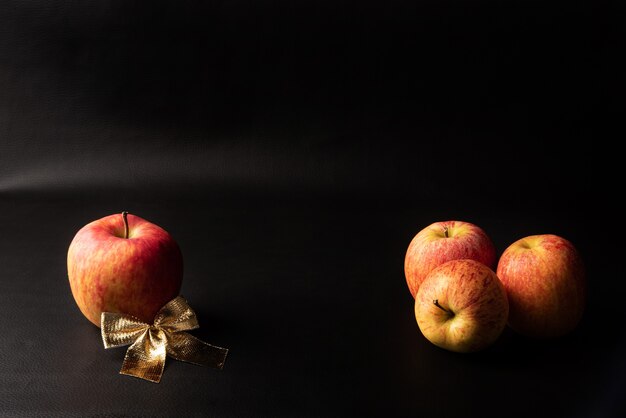 Pommes, belles pommes et arc doré disposés sur fond noir, portrait discret, mise au point sélective.
