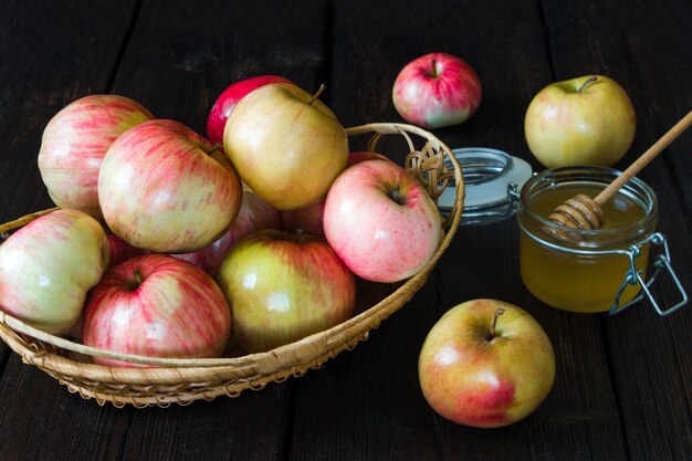 Photo pommes dans un panier et miel sur fond noir