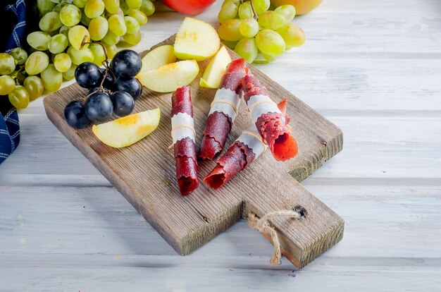 Pommes fraîches cueillies, raisins et pastille de fruits sur une surface sombre