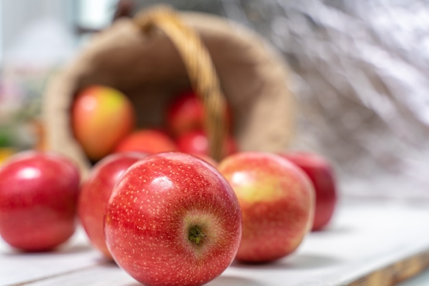 Pommes fraîches juteuses rouges sur un fond en bois renversé du panier