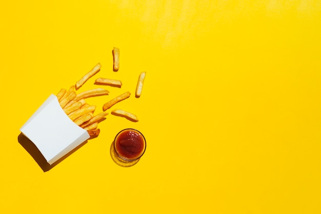 Pommes frites au ketchup sur fond jaune