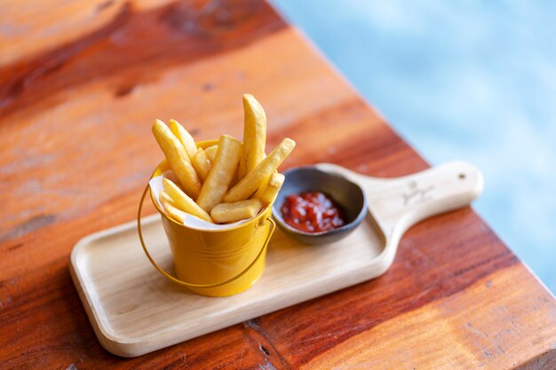 Pommes frites et ketchup sur planche de bois