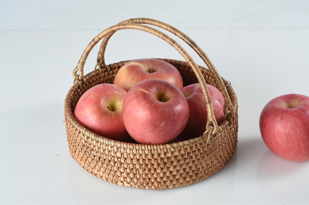 Pommes fruits dans panier en rotin,isolé sur fond blanc