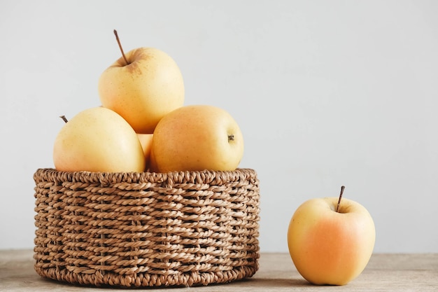 Pommes jaunes dans un panier en osier rond sur une table en bois Copiez l'espace vide pour le texte