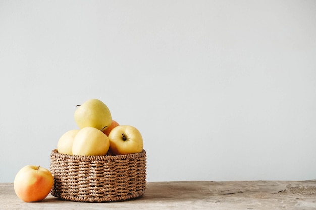 Pommes jaunes dans un panier en osier rond sur une table en bois Copiez l'espace vide pour le texte