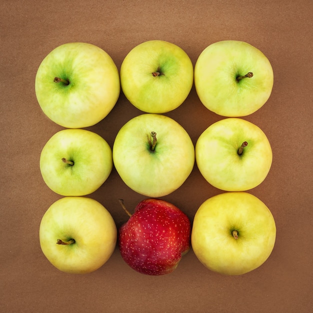 Pommes mûres juteuses jaune-vert au carré avec une pomme rouge.