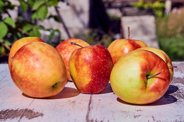 Pommes mûres juteuses rouges sur une vieille table en bois dans le contexte de l'automne nature