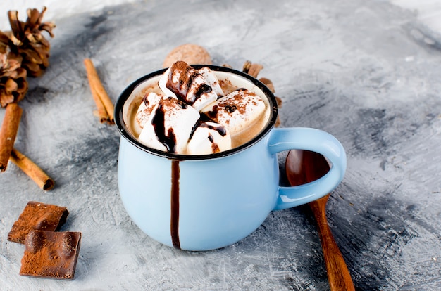 Pommes de pin, cacao dans une tasse bleue sur le vieux bois