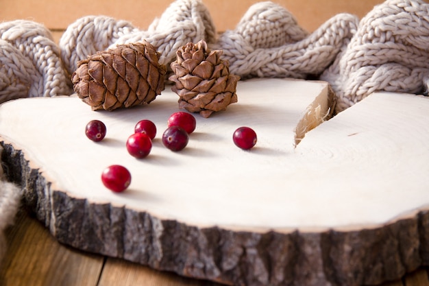 Pommes de pin et canneberges sur un support en bois.