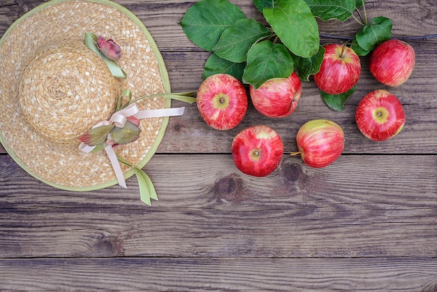 Pommes rouges et chapeau de paille sur fond de bois