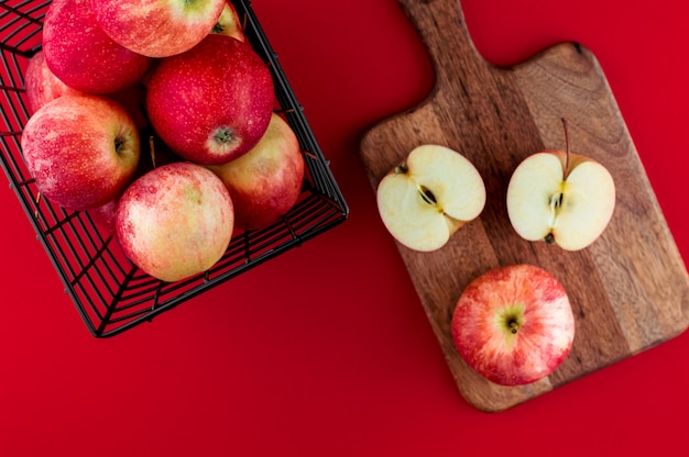 Pommes rouges dans le panier noir métallique sur le rouge profond. Vue de dessus plat composition laïque.