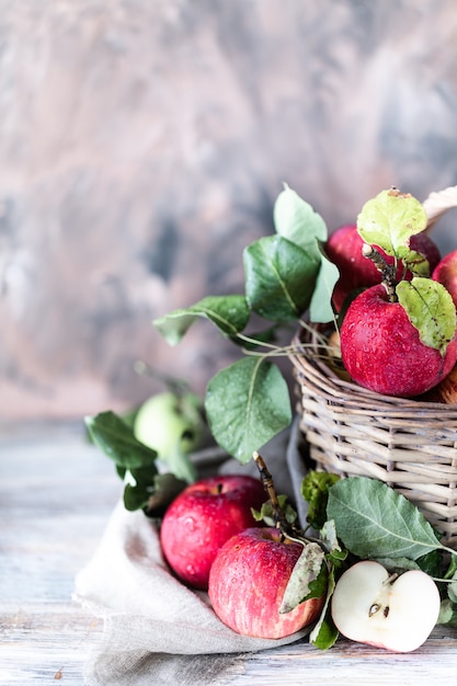 Pommes rouges dans un panier en osier sur une table en bois, table floue