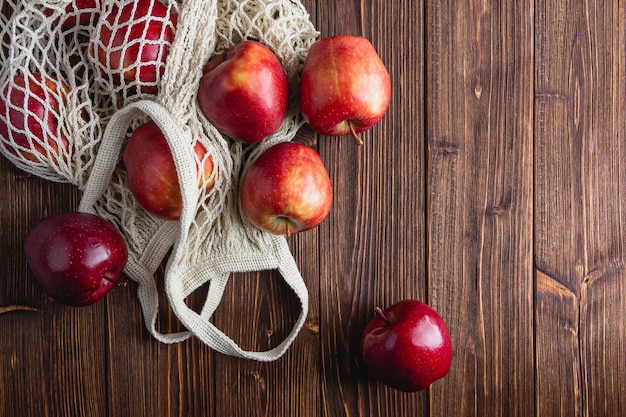 Pommes rouges dans un sac de grille sur un fond en bois