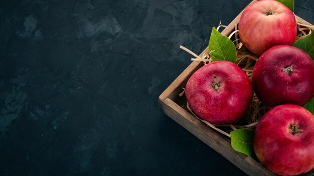 Pommes rouges fraîches dans une boîte en bois Aliments biologiques Sur fond noir Vue de dessus Espace libre pour le texte