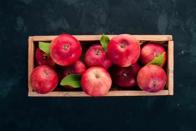 Pommes rouges fraîches dans une boîte en bois Aliments biologiques Sur fond noir Vue de dessus Espace libre pour le texte