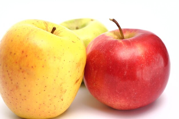 Pommes rouges, jaunes et vertes sur fond blanc