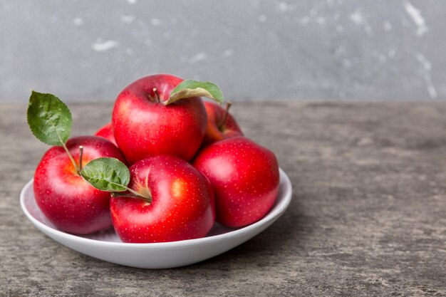 Pommes rouges juteuses dans un bol ou une assiette sur la vue de dessus de table Espace de copie