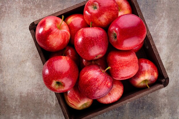 Pommes rouges mûres dans une boîte en bois. Vue de dessus avec un espace pour votre texte.