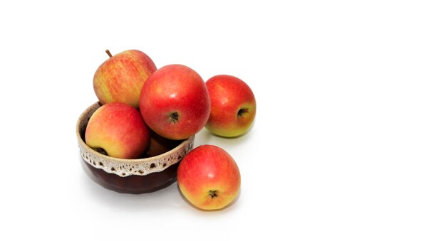 Des pommes rouges mûres dans un bol sur la table sur fond blanc