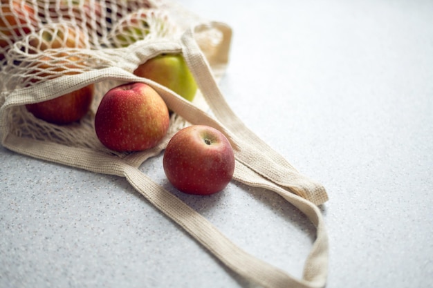 Pommes rouges mûres dans un sac écologique tissé blanc sur la table