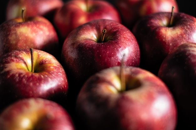 Des pommes rouges parfumées gisent dans une rangée sombre