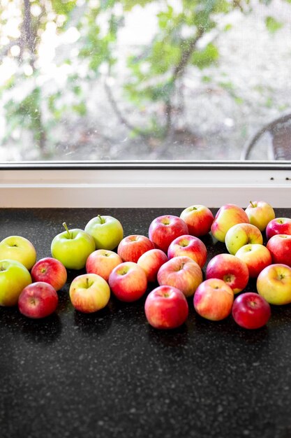 Des pommes rouges et rayées sur le rebord de la fenêtre Récolte de pommes précoces un jour d'été