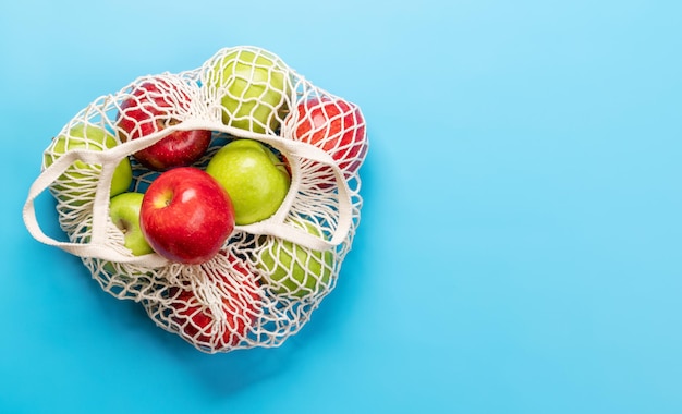 Pommes rouges et vertes dans un sac en filet sur bleu