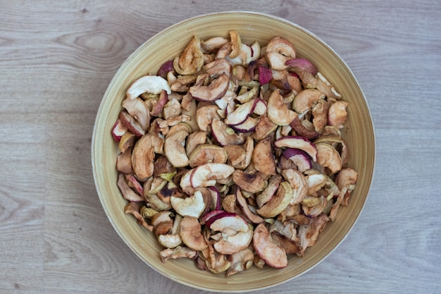 Pommes séchées dans une assiette en gros plan Les fruits secs des pommes sont dans une assiette en bois